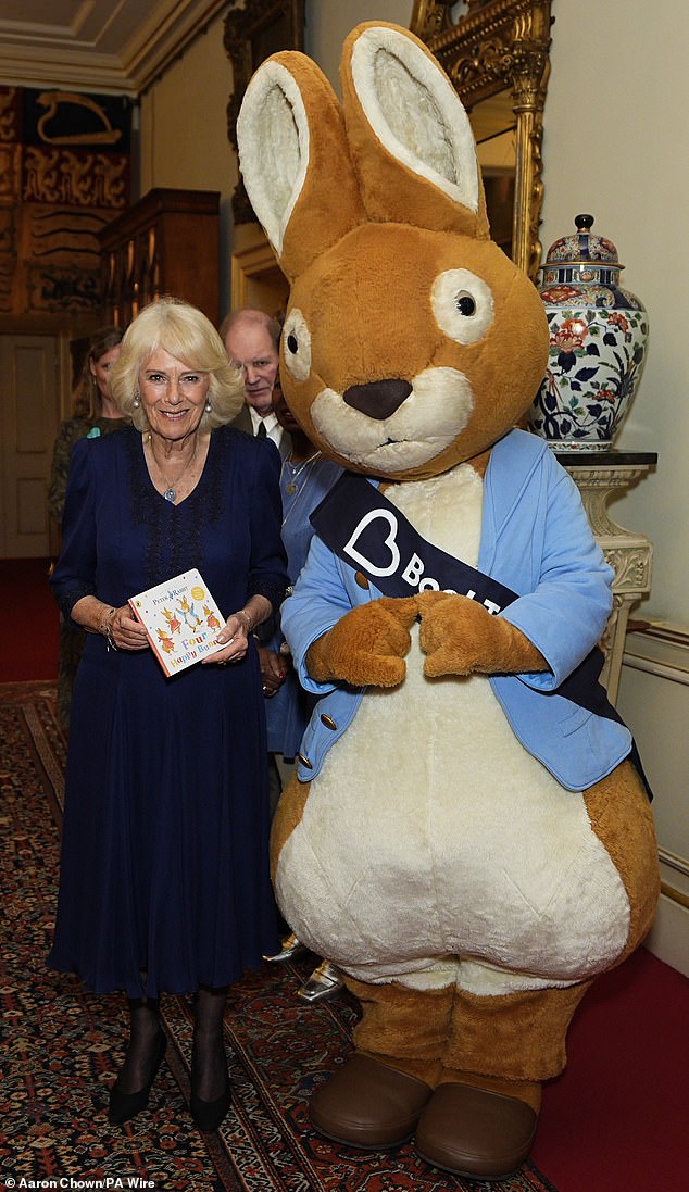 Queen Camilla is pictured beaming next to Peter Rabbit at an event at Clarence House today as she poses with the new book, Four Happy Bunnies